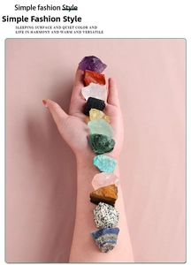 Macro display of 12 natural healing crystals on pink leather background in a vertical line