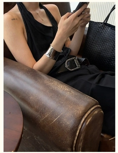Detailed view of a wide polished silver cuff bracelet on a model wearing a black top