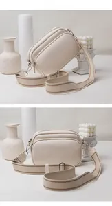 Detail view of cream white lychee leather crossbody bag with triple zipper compartments