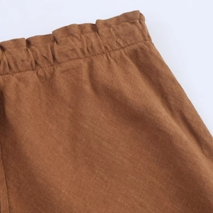 Detail of brown linen midi skirt showing the elastic pleated waistband and fabric texture