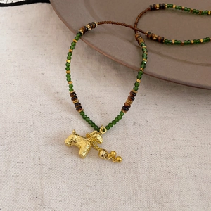 Macro detail of tiger eye crystal beads and vintage gold horse pendant on necklace