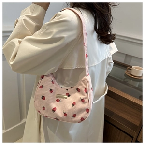 Corduroy armpit bag with strawberry print shown on model wearing a beige coat