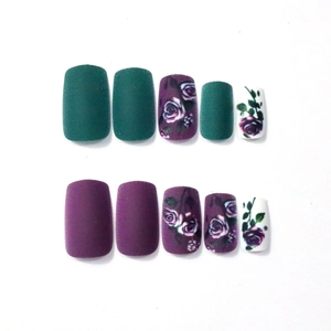 Detail view of square matte dark purple and green press-on nails with rose pattern