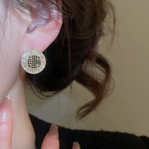 Close-up of gold plated round stud earring with black and white zircon stones