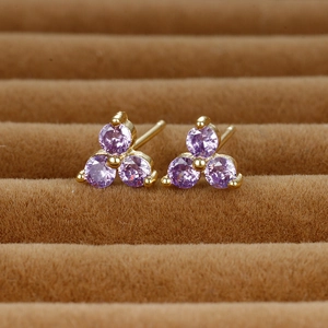 Detailed close-up of clover-shaped gold earrings with three purple zircon gemstones