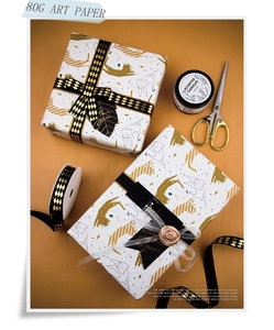 Detail of white gift wrap with golden leopard print and black gold ribbon on yellow background