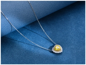 Detail shot of heart-shaped yellow gemstone pendant with double halo diamond setting