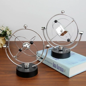 Kinetic orbital motion gadget on black base for creative home and office desk decoration