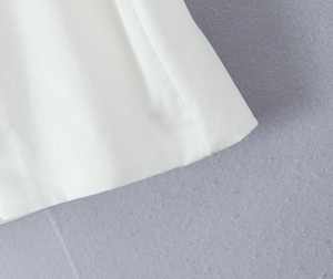 Detailaufnahme der weißen Köperstofftextur und der Nähte des kurzen Minikleides