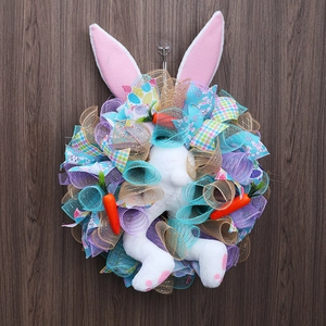Detail of Easter bunny wreath with plush ears and orange carrots on dark wood background