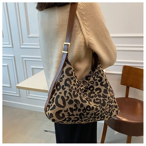 Detail of leopard print canvas bag with brown leather strap and golden buckle
