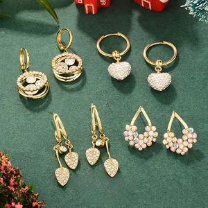 Detail of luxury Christmas gold tassel heart earrings on a festive green background