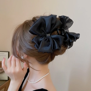 Dettaglio di un grande fermaglio per capelli in raso nero con fiocco e strass