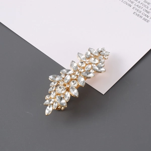 Sparkling leaf-shaped gold hair clip with crystal rhinestones on a minimalist background