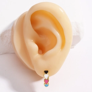 Detail of gold hoop earring with four colorful enamel hearts worn on a model ear