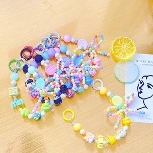 Colorful candy-beaded phone strap with heart and flower charms on a wooden surface