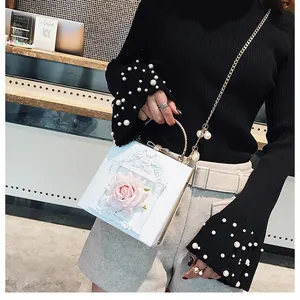 Detailed view of the 3D pink rose decor and gold handle on this white square box bag
