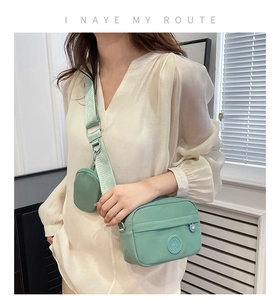 Detail of mint green oxford crossbody bag with matching round coin purse on shoulder strap