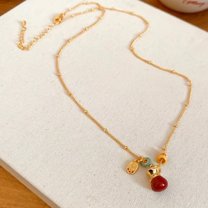 Detail of gold lucky bag necklace with red bead and Chinese character Fu charm