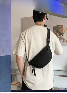 Close-up of black canvas chest bag with adjustable strap on model in home setting