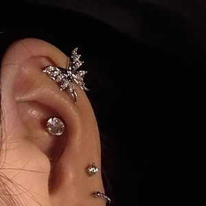 Close-up of silver butterfly ear cuff set with sparkling zircon on a female model