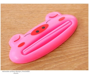 Close-up of pink pig-shaped manual toothpaste squeezer on wooden background surface