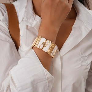 Detail of a chunky gold metal and white enamel geometric square stretch bracelet
