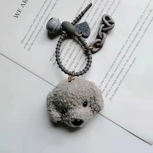 Detailed view of grey teddy dog keychain with bell and heart charm on text background