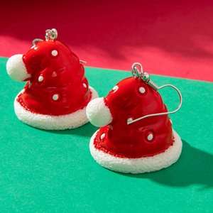 Close-up of red and white Christmas hat earrings with polka dots on a festive background