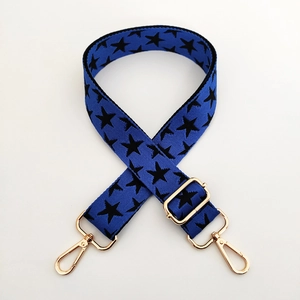 Macro shot of blue wide bag strap with black stars and adjustable golden metal hooks