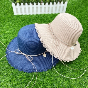 Détail d'un chapeau de paille avec bord en dentelle marine et breloques en perles