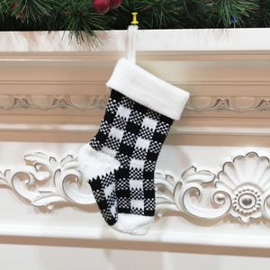 Close-up of black and white checkered knitted Christmas stocking on a festive fireplace