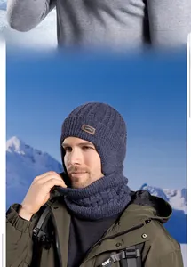 Detail of dark blue thermal knit balaclava with mountain patch against a snowy peak
