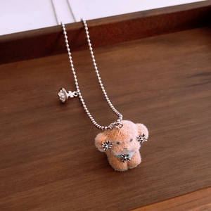 Detail of plush brown dog pendant with saturn charm and silver bead necklace chain