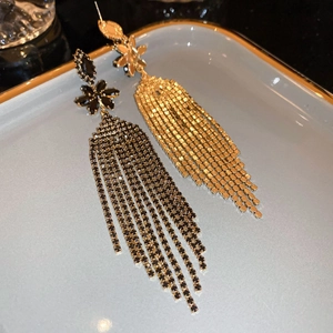 Dettaglio macro di orecchini floreali scuri con frange di nappe in strass a cascata