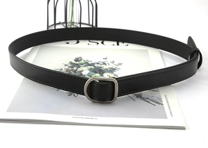 Close-up of black faux leather belt with a matte gunmetal D-ring buckle on a clean background