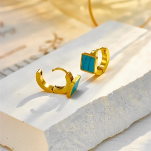 Golden geometric square turquoise hoop earrings on a white stone display stand