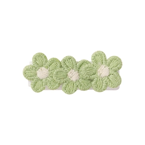 Close-up of floral knit hair clip with detailed green embroidery and white centers