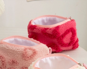 Detail view of plush makeup bags in pink and beige with embossed heart patterns