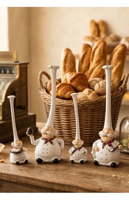 Macro view of four resin chef figurines with long hats and culinary accessories