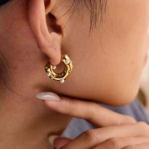 Detail of gold chunky hoop earring with white pearls and sparkling crystals on model