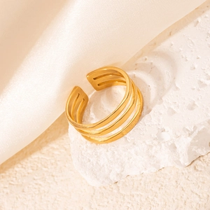 Détail d'une bague ouverte à trois couches en acier titane doré avec texture brossée