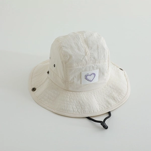 Detail of cream nylon bucket hat with heart patch and adjustable black chin strap