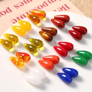 Close-up of colorful resin teardrop beads for jewelry making arranged on a white tray