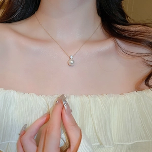 Detail of elegant gold pearl necklace with zircon drop worn on collarbone by a model