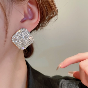Close-up of luxury geometric square stud earrings with crystal pavé on a female model