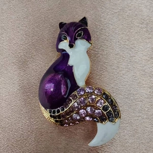 Détail macro de la broche renard montrant l'émail violet et les strass colorés