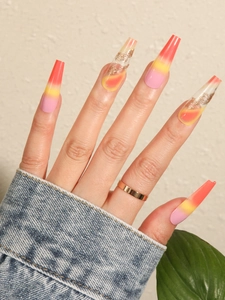 Detailed view of long coffin press-on nails with pink orange gradient and gold glitter swirls