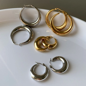 Set aus polierten Gold- und Silber-Creolen in Keramikschale, minimalistischer Stil