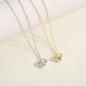 Detailed view of polished heart pendant necklaces in gold and silver metallic finishes